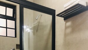 Un baño con inodoro, cabina de ducha de vidrio y un perchero para toallas.