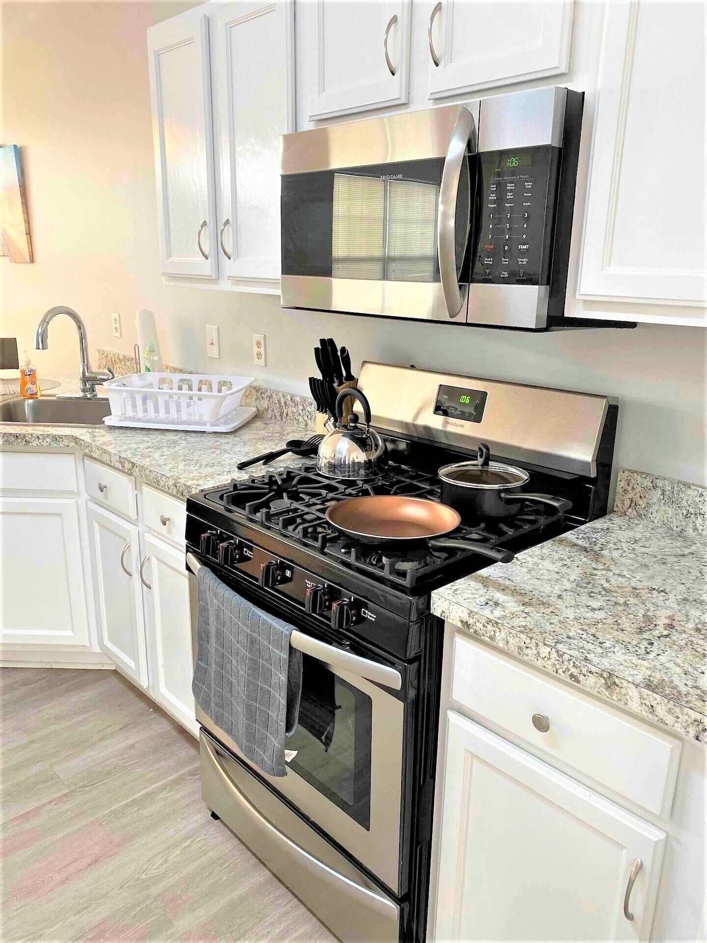 A modern kitchen with white cabinets, stainless steel appliances, and granite countertops.