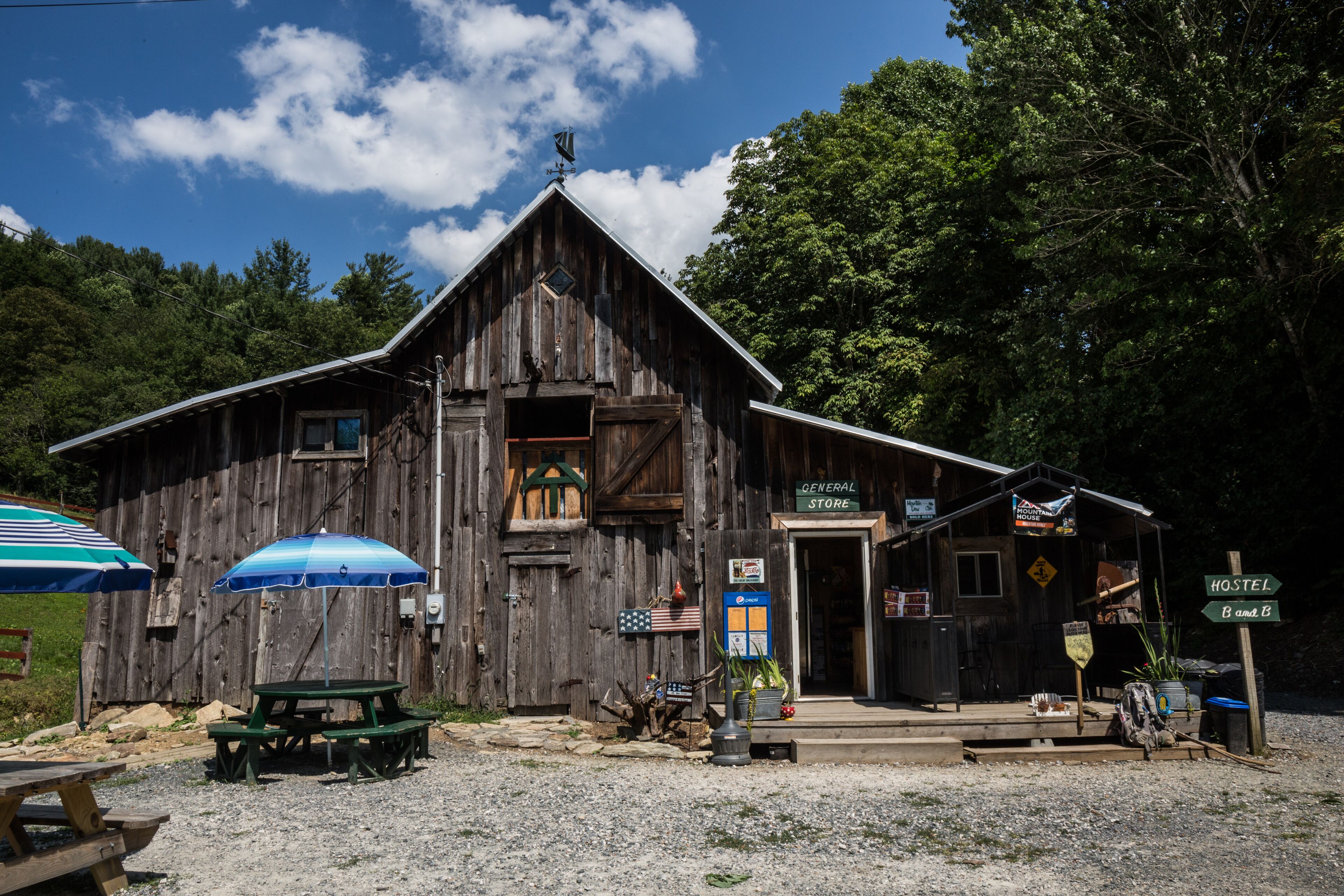 A rustic wooden building with a general store sign, a bench, and a sign indicating hostel B and B.