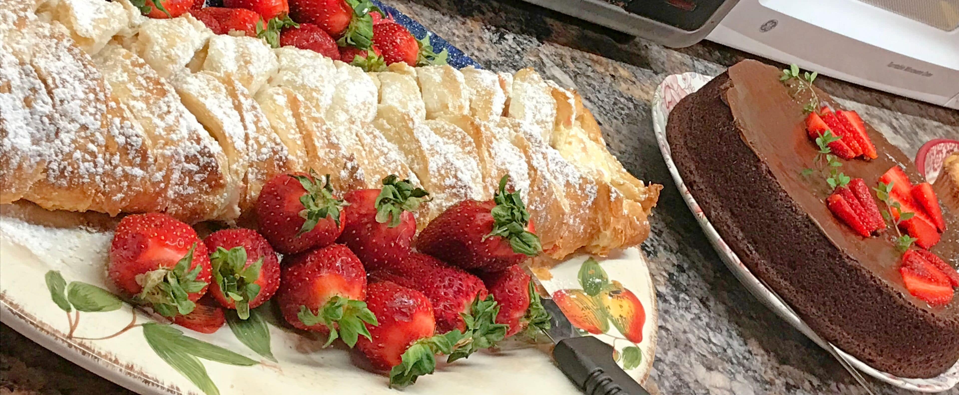 A dessert tray with a layered pastry and strawberries.