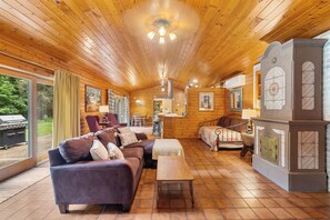 A cozy cabin interior with wooden walls, a sofa, a bed, and a dining area. - Secluded Family- and Pet-Friendly Cottage (New Era)