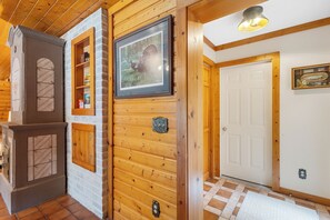 Un intérieur en bois avec une cheminée, un tableau encadré et une porte.