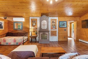 A cozy log cabin interior with a bed, a fireplace, and a dining area. - Secluded Family- and Pet-Friendly Cottage (New Era)