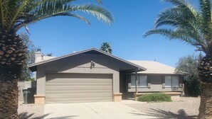 A single-story house with a garage, surrounded by palm trees and a clear blue sky. - Near Starr Pass-Downtown- U of A  3 Bedoom Home (Tucson)