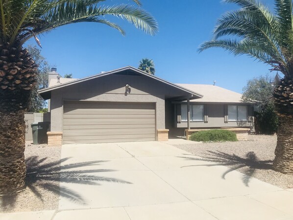 A single-story house with a garage, surrounded by palm trees and a clear blue sky. - Near Starr Pass-Downtown- U of A 3 Bedoom Home (Tucson)