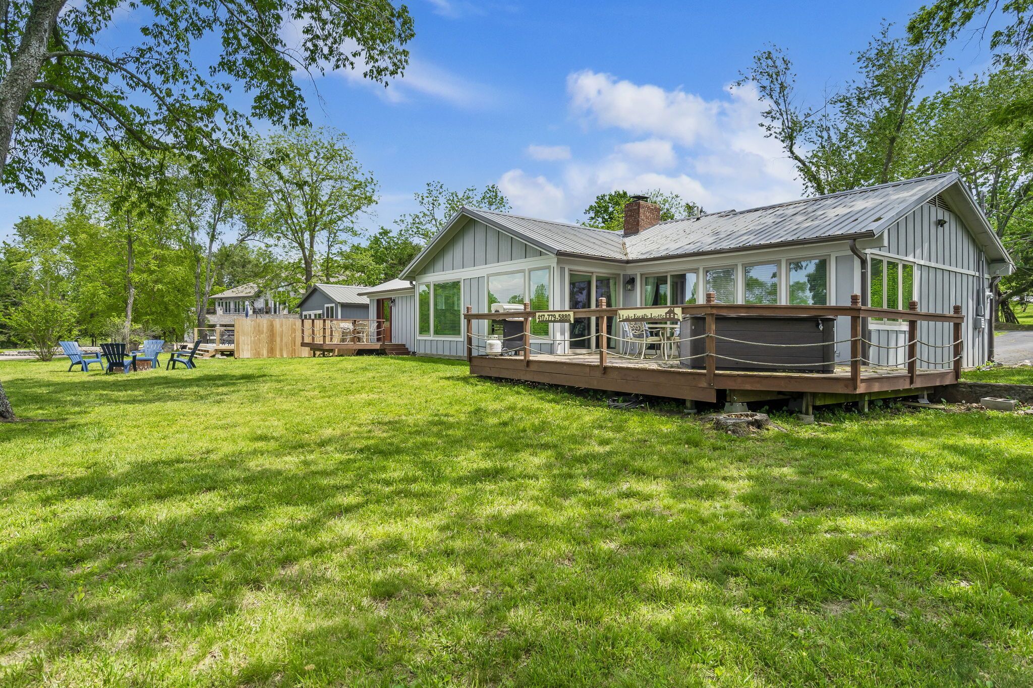 Un chalet rustique doté d’une terrasse et d’un porche abrité, entouré d’une végétation luxuriante et d’arbres.