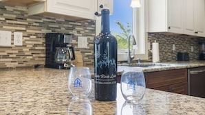 A kitchen with a granite countertop, a wine bottle, and two glasses.