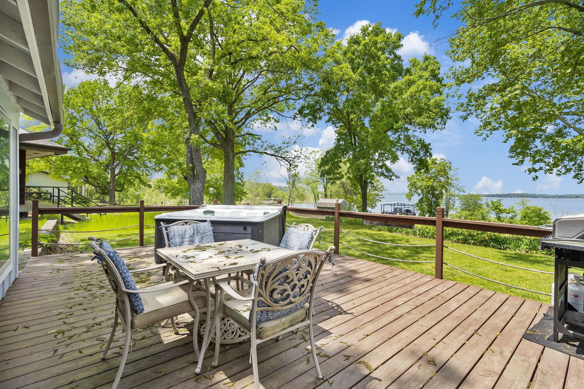 Une terrasse en bois avec une table et des chaises, d’où l’on a vue sur un lac et des arbres.