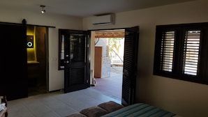 Una habitación con una cama, un banco, una puerta y una ventana.