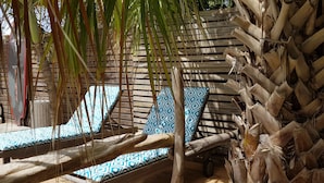 Una terraza de madera con dos sillas reclinables, una con cojín estampado y otra con cojín de color liso.