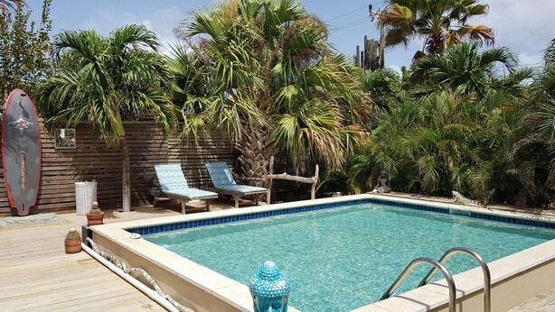 Una piscina con sillones de descanso y una tabla de surf.