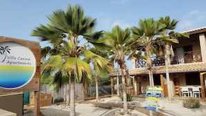 Apartamentos Villa Carina con un letrero que indica indicaciones hacia la oficina, Bachata, Merengue, Salsa y Kimbell.