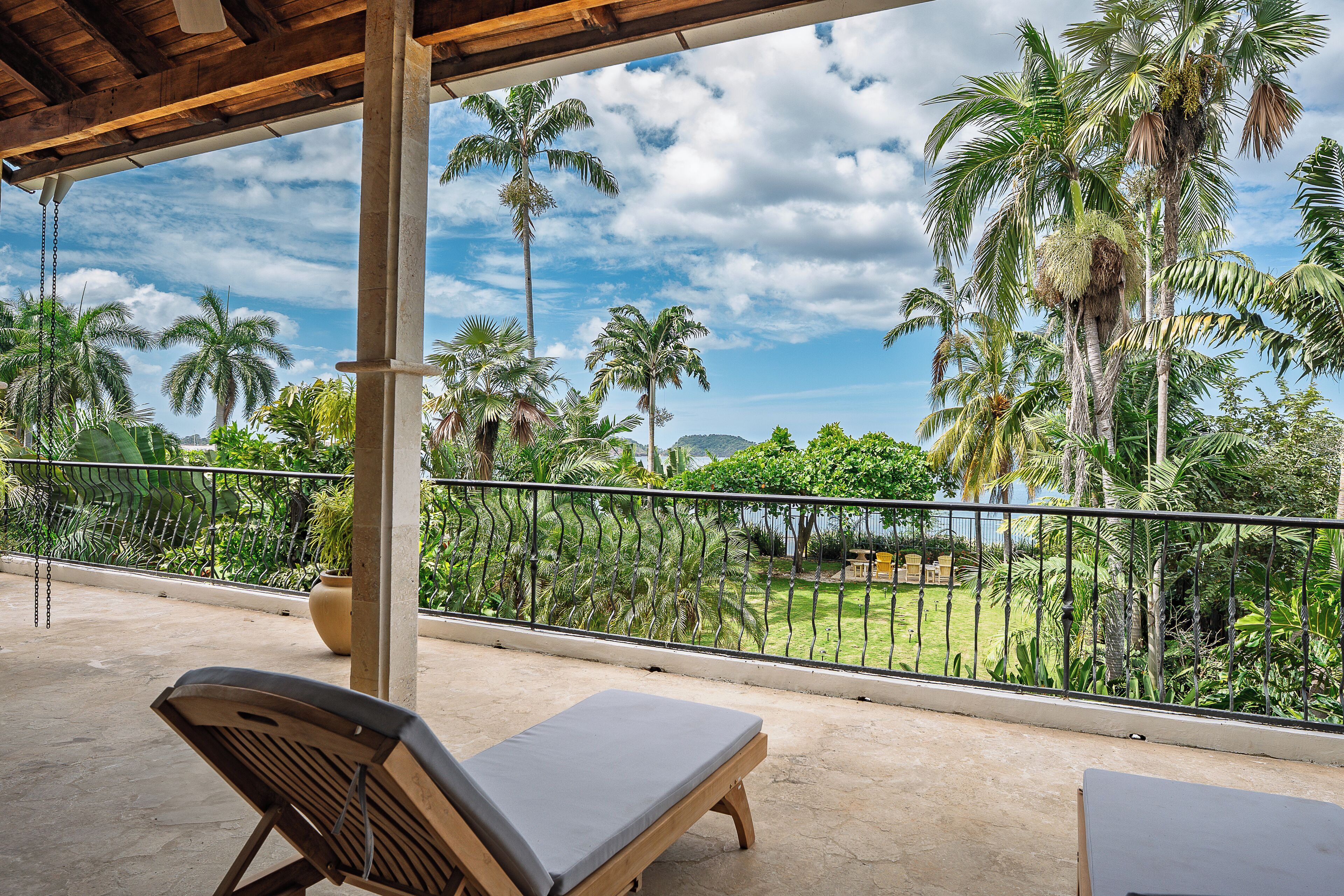 Un balcon avec vue sur des palmiers et une zone verdoyante.