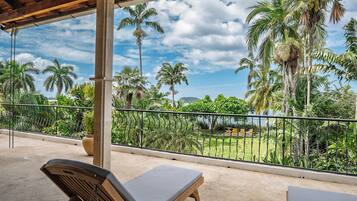 Un balcon avec vue sur des palmiers et une zone verdoyante.