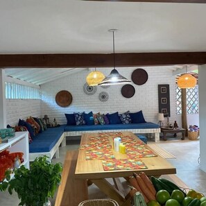 Una sala de estar acogedora con un sofá azul, una mesa de madera con frutas y decoración en la pared.