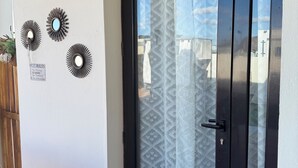 Una puerta con un cortinero estampado, un cartel con las normas de la piscina y tres espejos adosados a la pared.