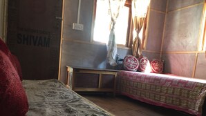 Una habitación con cama, una mesita y una ventana con cortinas.