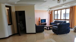 Un salón espacioso con un televisor grande, dos sofás, una mesa de centro y una alfombra estampada.