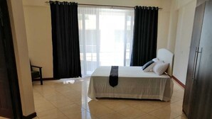 Habitación de hotel con cama, una silla, un armario y vistas por la ventana.