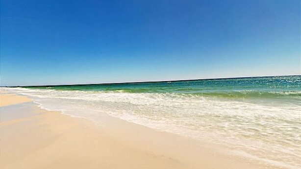 A beach with clear skies and calm waters. - Gorgeous beach views Walk to beach Theater room (Gulf Shores)