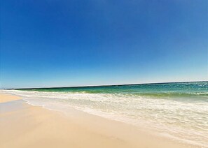 Uma praia com céu claro e águas calmas.