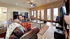 A spacious living room with a leather sofa, a coffee table, and a ceiling fan. - Gorgeous beach views Walk to beach Theater room (Gulf Shores)