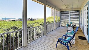 A covered porch with a view of a vineyard, wooden flooring, and two blue chairs. - Gorgeous beach views Walk to beach Theater room (Gulf Shores)