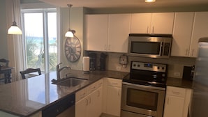 A modern kitchen with stainless steel appliances, white cabinets, and a large window with a view. - September Reduced Rates !! VIP Beach Chair service Included (Panama City Beach)