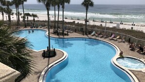 A pool with a curved design, surrounded by palm trees and a beach view. - September Reduced Rates !! VIP Beach Chair service Included (Panama City Beach)