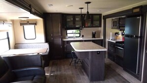 A compact RV kitchen with dark cabinetry, a central island, and a dining area with a bench. - Waterfront Private Campground-Two extra RV hookups available - 50.00 per night   (Ontonagon)
