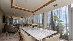 A spacious living area with a large marble table, comfortable seating, and a view of the ocean. - HYDE HOUSE NEW (Hollywood)