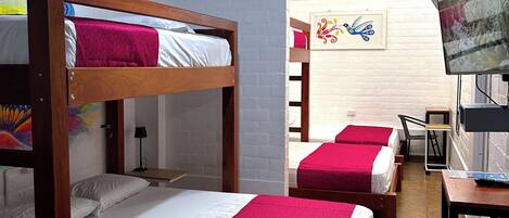 Una habitación tipo dormitorio con literas, un escritorio, una silla y un televisor.