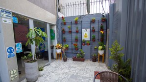 A courtyard with a tiled floor, potted plants, and a wicker chair. - Magdalen House (Lima)