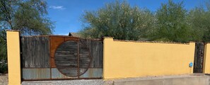 Pared amarilla con una rústica verja de madera que presenta un gran ventanal circular.