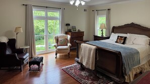 A bedroom with a large bed, a chair, a desk, and a window with curtains. - Bourbon Estate  sleeps 12, 6 BRs, 47ac of Waterfalls, Meadows and Creek (Bardstown)