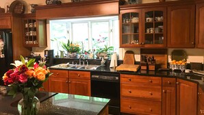A kitchen with wooden cabinets, a black countertop, and a window with plants. - Bourbon Estate  sleeps 12, 6 BRs, 47ac of Waterfalls, Meadows and Creek (Bardstown)