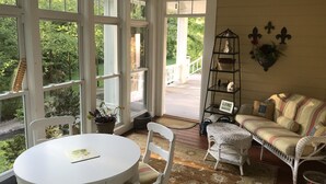 A room with a white round table and chairs, a striped sofa, and a bookshelf. Large windows offer a view of greenery outside. - Bourbon Estate  sleeps 12, 6 BRs, 47ac of Waterfalls, Meadows and Creek (Bardstown)