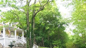 A house with a porch, a stone wall, and a garden with a fountain. - Bourbon Estate  sleeps 12, 6 BRs, 47ac of Waterfalls, Meadows and Creek (Bardstown)