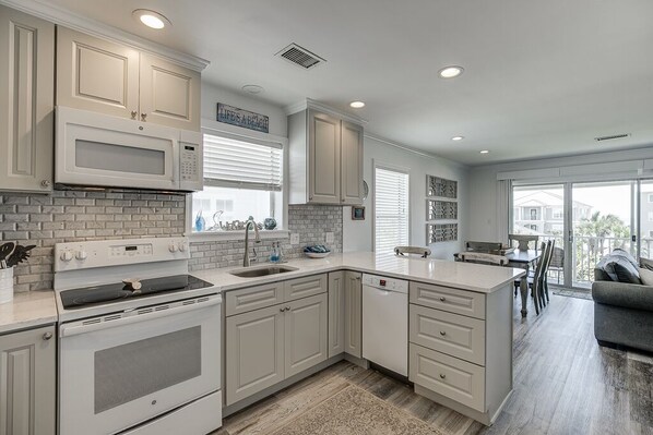 A modern kitchen with white cabinetry, a built-in microwave, and a large island with a sink.