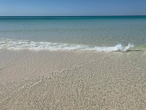 A beach with clear shallow waters and a sandy shore.