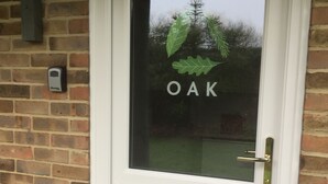 Una puerta blanca con un panel de vidrio que muestra la palabra "OAK" y un diseño de hoja.