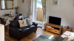 Una sala de estar con sofá, mueble para televisor y comedor con mesa y sillas.