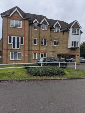 A multi-story residential building with a brick facade, multiple windows, and a gated parking area. - Oaklawn Serviced Apartments (Woking)