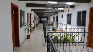 A corridor with potted plants, a balcony with a wrought iron railing, and a staircase leading to an upper floor. - Hotel Casa Blanca (Tuxtla Gutierrez)