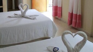 A hotel room with two beds, a bathroom, a TV, and a balcony with pink curtains. - Hotel Casa Blanca (Tuxtla Gutierrez)