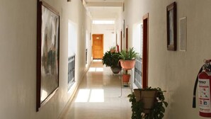 A hallway with framed pictures on the walls, potted plants, and a fire extinguisher. - Hotel Casa Blanca (Tuxtla Gutierrez)