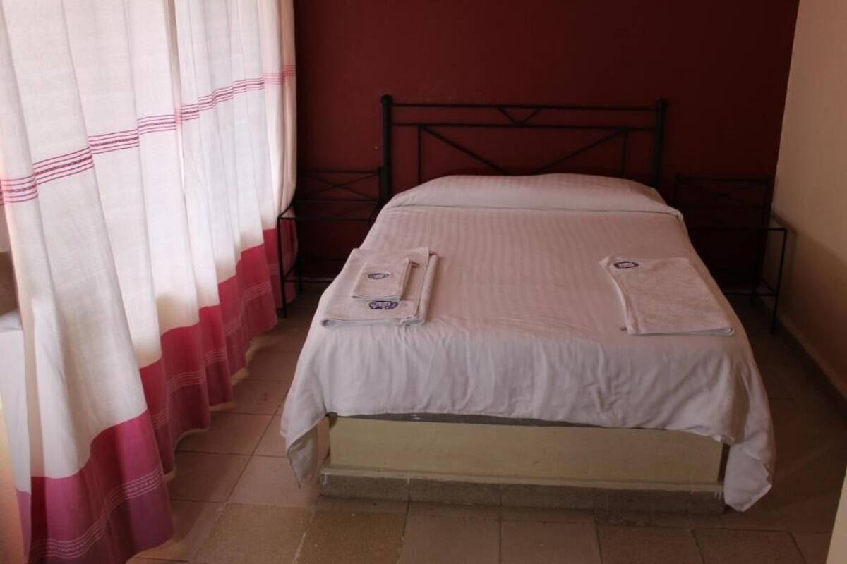 A single bed with a metal frame, a white bedspread, and two pillows.
