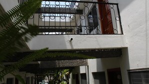A building with a white exterior, a balcony with a metal railing, and a window with a red door. - Hotel Casa Blanca (Tuxtla Gutierrez)
