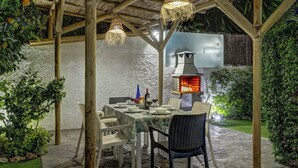 An outdoor dining area with a thatched roof, wicker furniture, and a built-in grill. - Villa Conchita Torremolinos (Torremolinos)
