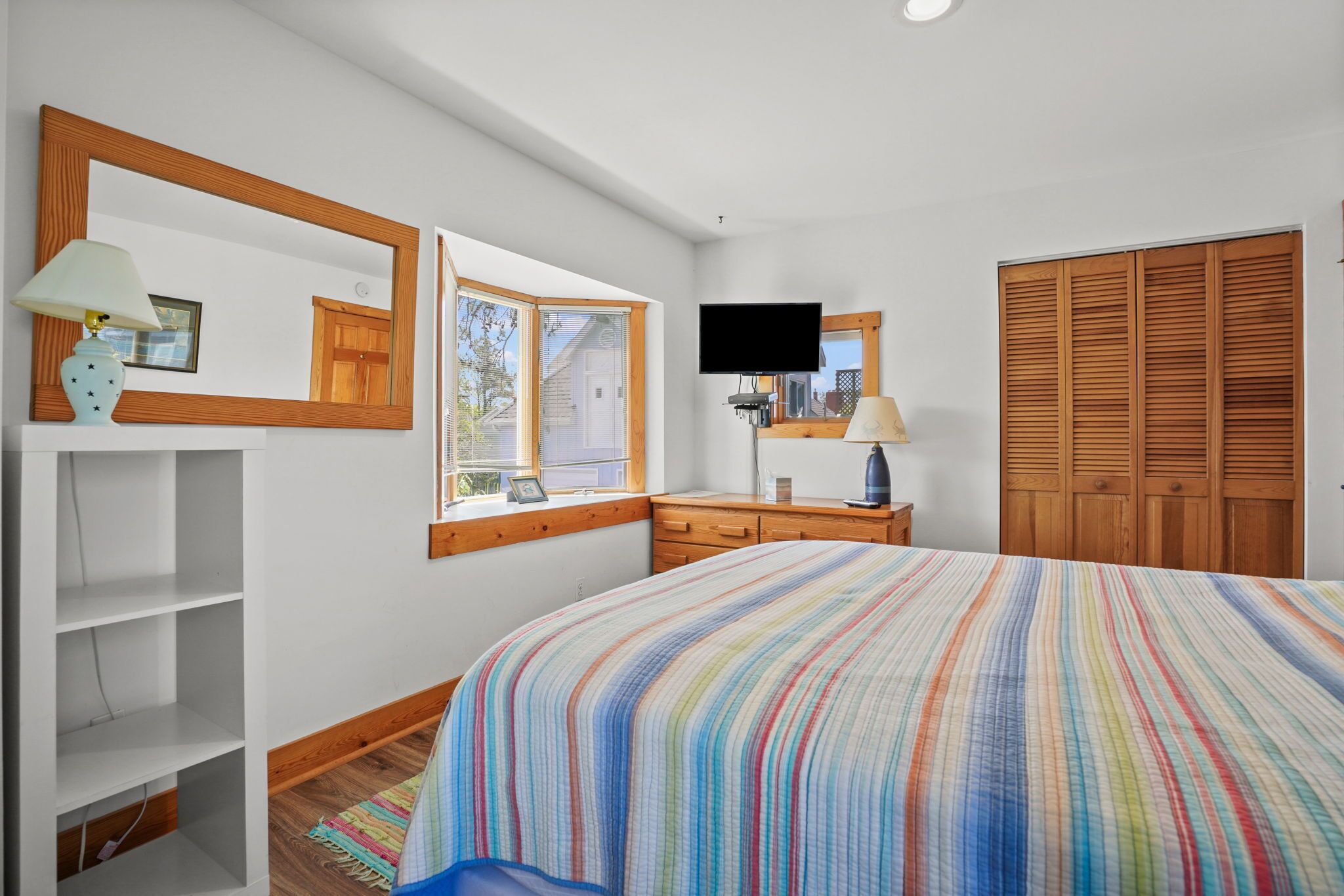 Une chambre à coucher avec un grand lit, une télévision, une armoire en bois et une fenêtre donnant sur l’extérieur.